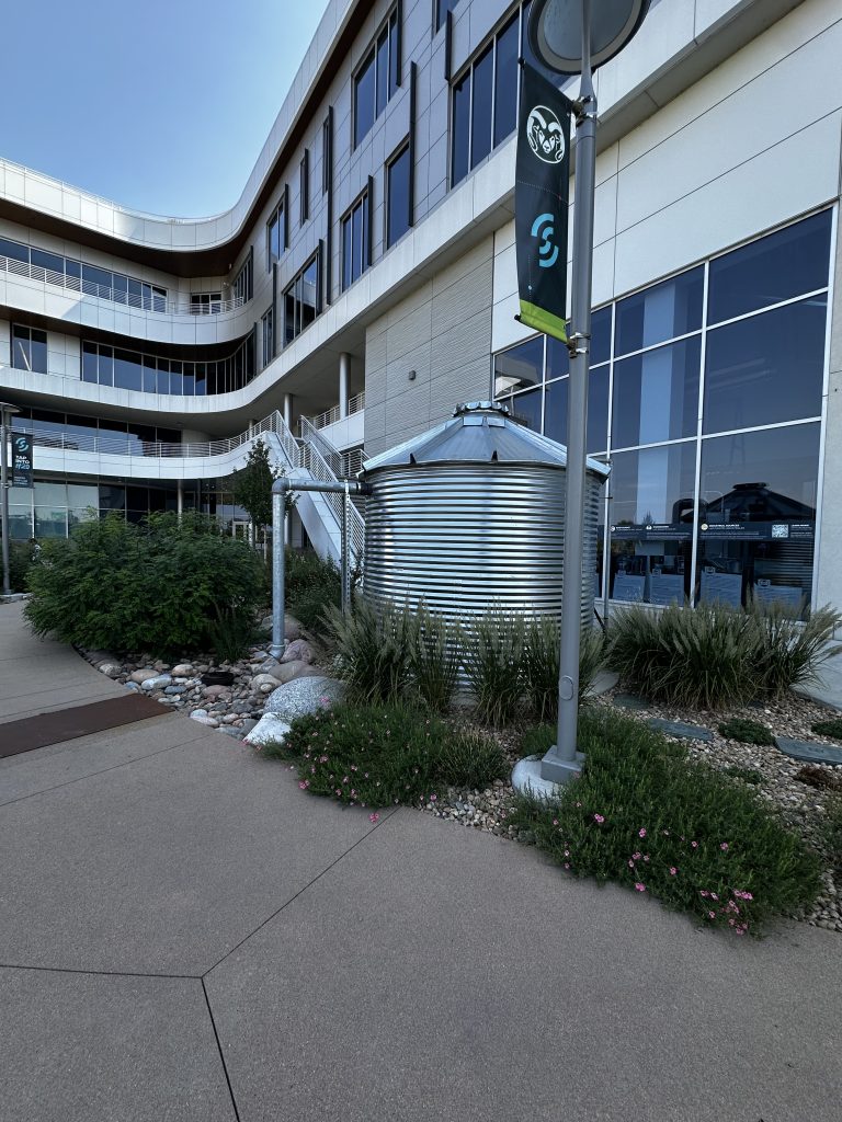 Rainwater harvesting tank with green plants at CSU Spur Backyard.