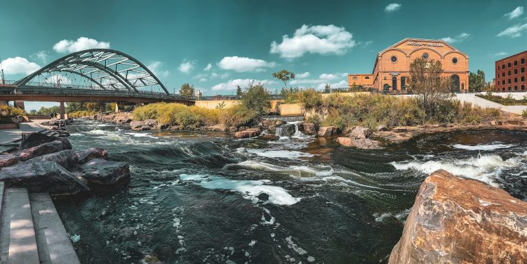 A photo of the South Platte River from Confluence Park. A bridge and a Denver store are visible.